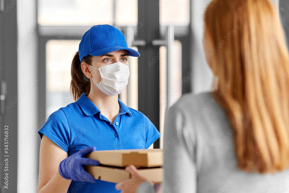 health protection, safety and pandemic concept - delivery woman in medical face mask and gloves giving pizza boxes to female customer at office
