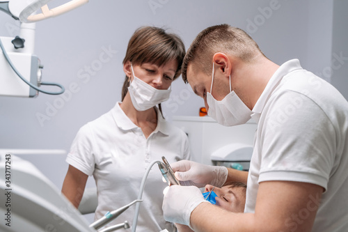 Professional dentist and nurse doing operation on female patient. A team of dentists with client in a dental office  oral care  healthy teeth  stomatology concept
