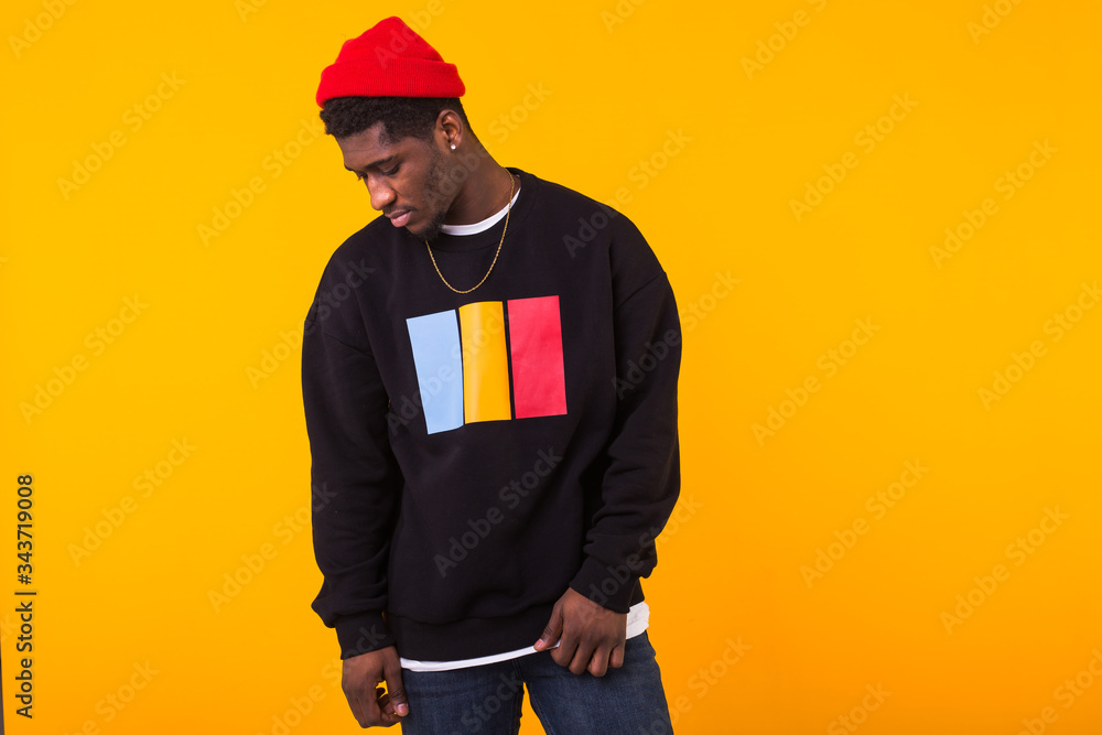 Portrait handsome young black man dressed in jeans and sweatshirt on yellow background. Street fashion and modern youth culture. Portrait handsome young black man dressed in jeans and sweatshirt on yellow background. Street fashion and modern youth culture.
