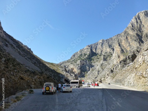 Mountain road among rocks. Cars are on the side of the road. Clear blue sky. © kornetka