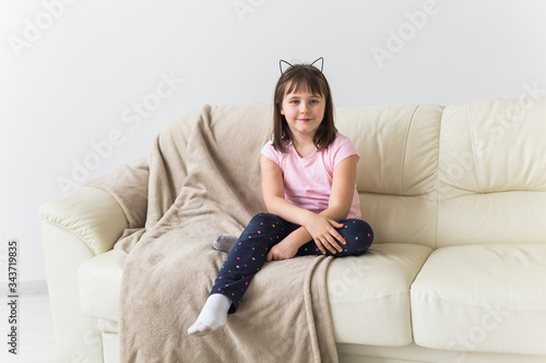 Cute girl kid with cat ears sitting on the couch. Children and childhood concept.
