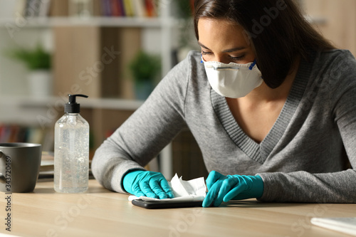 Woman disinfecting phone from coronavirus at night at home