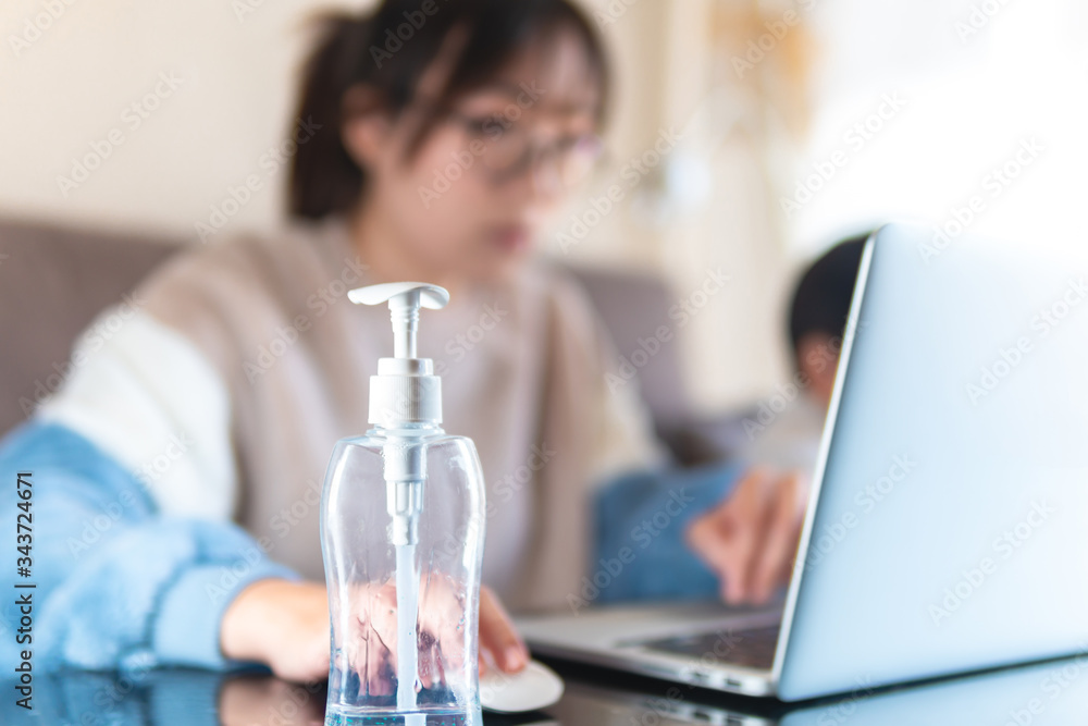 Empty bottle of hand sanitizer alcoholic gel at home office. Young freelance woman working at home while taking care of kids. Remote work during coronavirus pandemic Empty bottle of hand sanitizer alcoholic gel at home office. Young freelance woman working at home while taking care of kids. Remote work during coronavirus pandemic