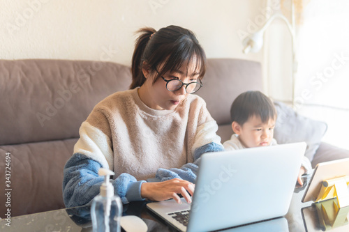 Woman working from home with kid children.  Young woman and cute child using laptop and tablet. Freelancer home workplace. Female business. Social distancing. Working from home. Stay home