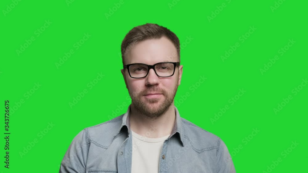 Handsome caucasian man with beard putting on glasses and looking at camera. Isolated shot at green screen. Portrait of cheerful guy in 4K, UHD Handsome caucasian man with beard putting on glasses and looking at camera. Isolated shot at green screen. Portrait of cheerful guy in 4K, UHD