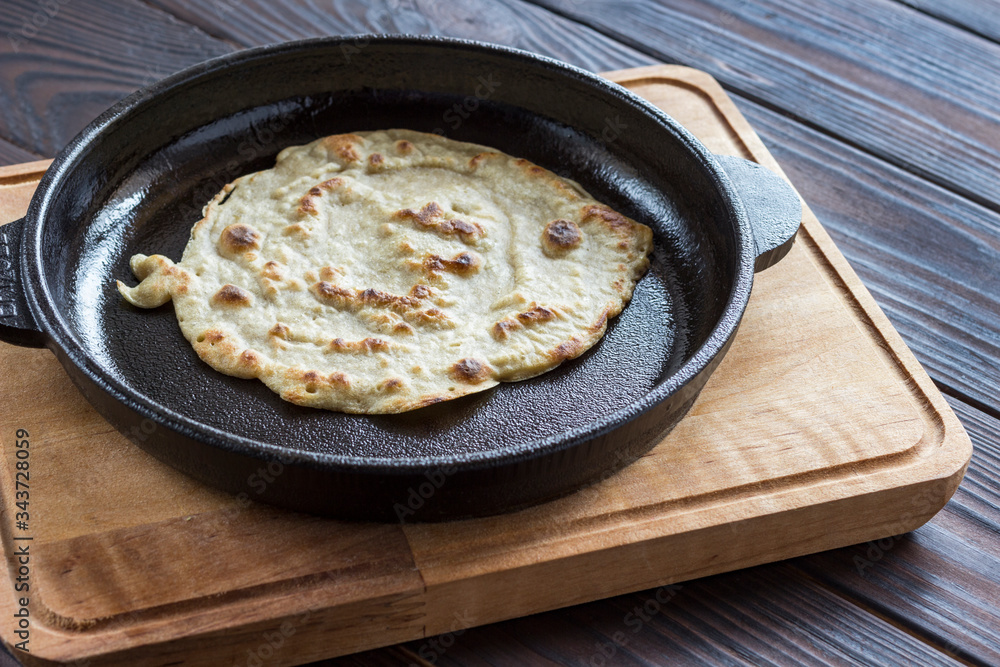 Pita bread in pan on dark wooden background. Natural food.