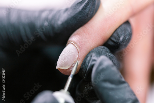 Process manicure close-up. Preparation for hardware manicure. Beautician in rubber gloves cuts the cuticle and processes nails.