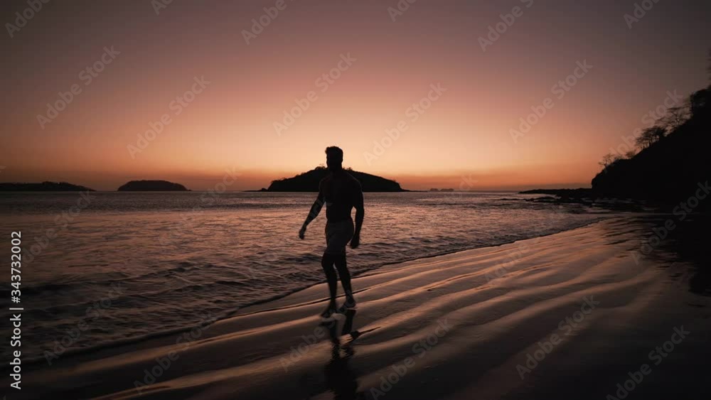 A man enjoying a walk on the beach of Costa Rica during sunset - wide shot A man enjoying a walk on the beach of Costa Rica during sunset - wide shot