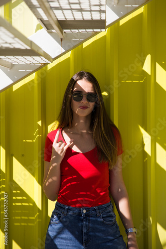 Trendy young woman standing by the yellow wall