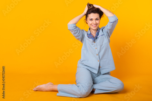 Close up young woman in blue home wear. Isolated on yellow background. Pajama concept. © satura_