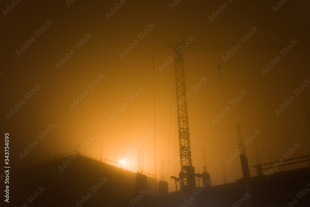 Tower crane at construction site in the misty morning sunlight