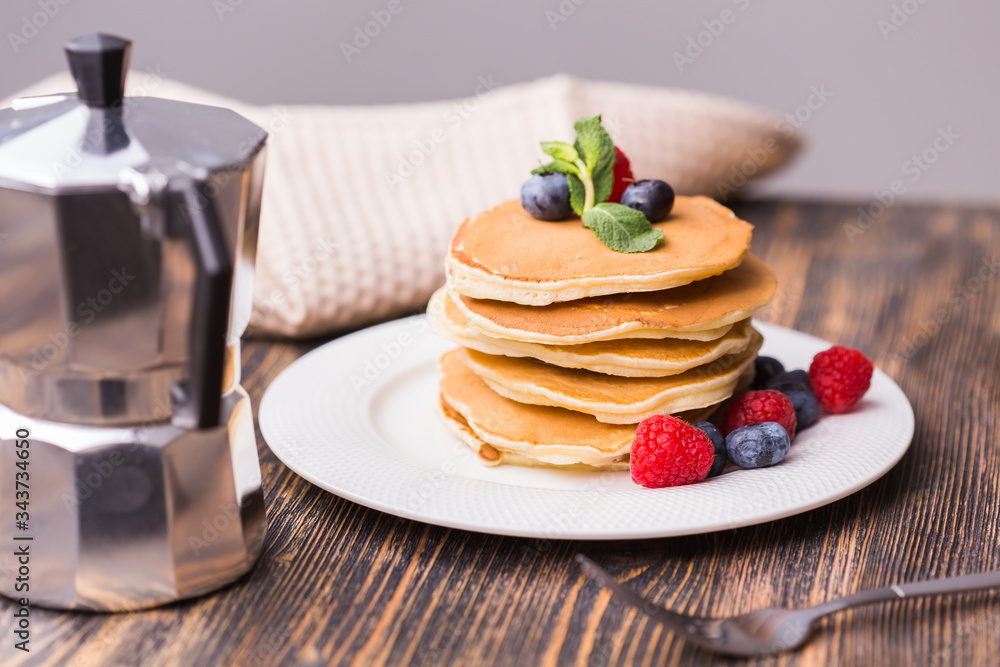 Pile of pancakes with blueberries and raspberries for breakfast on wooden table. Pile of pancakes with blueberries and raspberries for breakfast on wooden table.