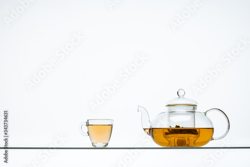 several tea glasses and a teapot on a glass table with a white background