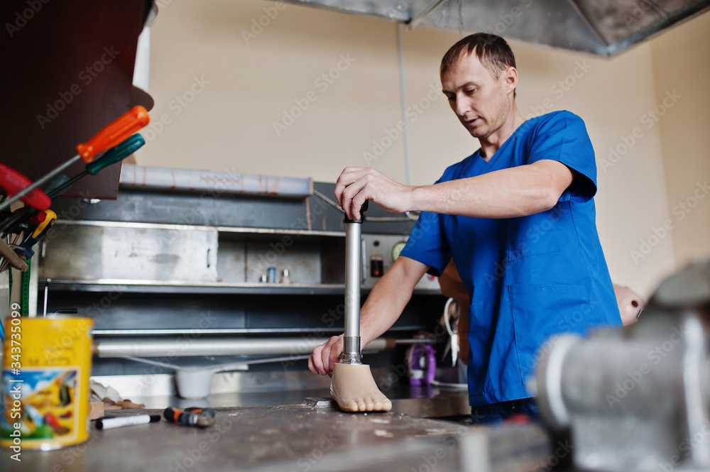 Prosthetist man making prosthetic leg while working in laboratory. Prosthetist man making prosthetic leg while working in laboratory.