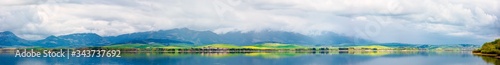 panorama of lake in mountains. cloudy day in springtime. beautiful scenery of high tatra mountains in dappled light. gorgeous landscape of liptovska mara, slovakia