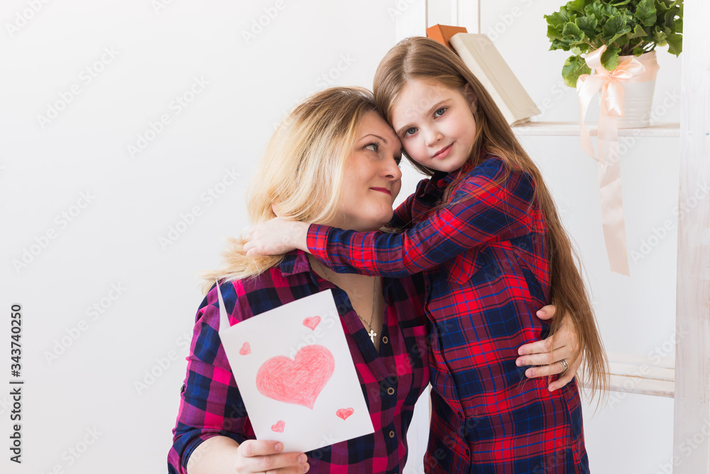 Happy mother's day. Child daughter congratulates mom and gives her postcard. Mum and kid girl smiling and hugging. Family holiday and motherhood.