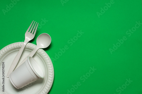 Fényképezés disposable spoon, fork, glass and plate of corn starch on a green background