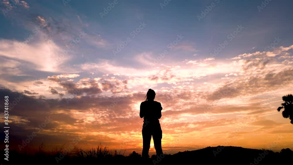 silhouette of very happy women stand on middle of scene and hand up in the air too many time during sunset as slow motion short silhouette of very happy women stand on middle of scene and hand up in the air too many time during sunset as slow motion short