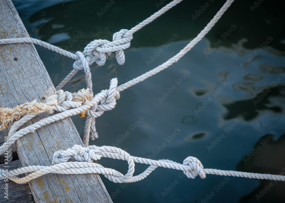Fototapeta premium knots on sea ropes are tied to a wooden Board or pier. The concept of safety on the water.