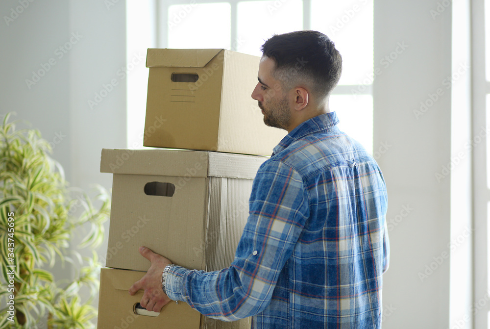 A moving man sitting on the floor in empty apartment, Among the Boxes, Checking the List of Things A moving man sitting on the floor in empty apartment, Among the Boxes, Checking the List of Things