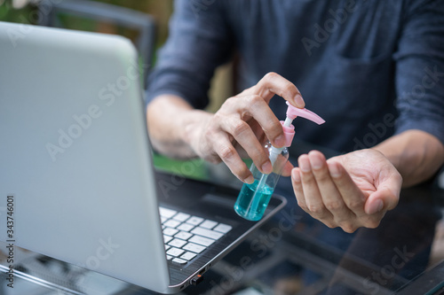 Washing hands by alcohol sanitizers or alcohol gel, before work from home.