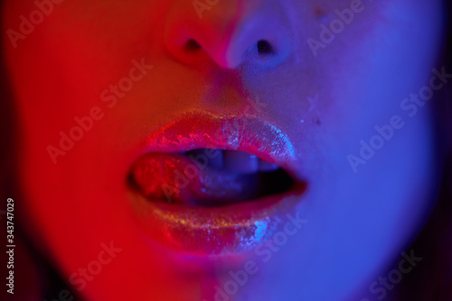 Beautiful girl, trendy glowing makeup, metallic silver lips. High fashion model woman in colorful bright neon lights red and blue.