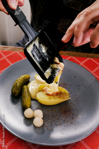 Swiss traditional dish called raclette including steamy potatoes, melted cheese and pickles eaten at christmas and wintertime.