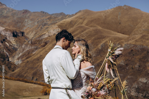 dynamic wedding photo of brides at the top of the mountain, happy loving couple hugging and kissing during wedding photo session