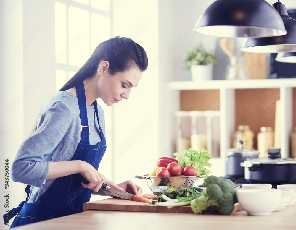 Young woman cutting vegetables in kitchen at home Young woman cutting vegetables in kitchen at home