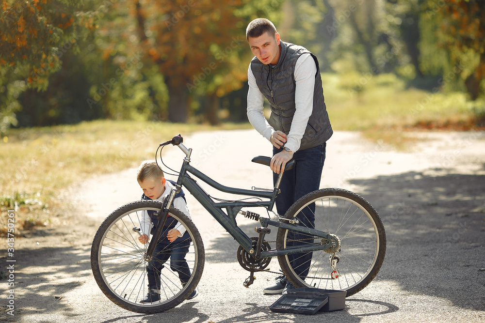Family in a park. Father with son. People repare the bike.