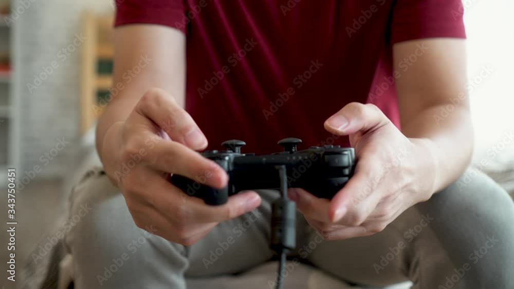 Close up of young man holding game controller while playing video console game. Asian guy using gamepad joystick at home. Close up of young man holding game controller while playing video console game. Asian guy using gamepad joystick at home.