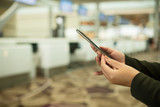 people hands use cellphone at counter Check-in airport on background with bokeh, check flight number on mobile phone in airport