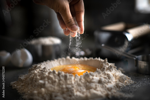 Process of making homemade wholewheat pasta in a kitchen with pasta sheet roller. Close up view. Dark photography