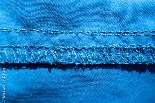 Overlock seam on blue synthetic fabric. Macro. Top view.
