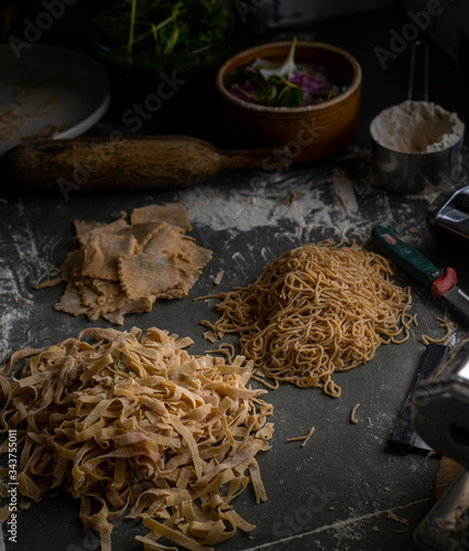 Process of making homemade wholewheat pasta in a kitchen with pasta sheet roller. Close up view. Dark photography
