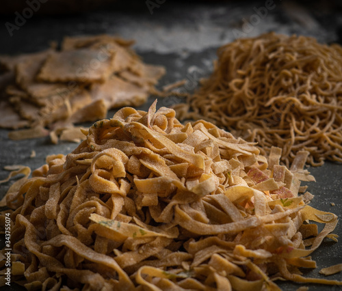 Process of making homemade wholewheat pasta in a kitchen with pasta sheet roller. Close up view. Dark photography