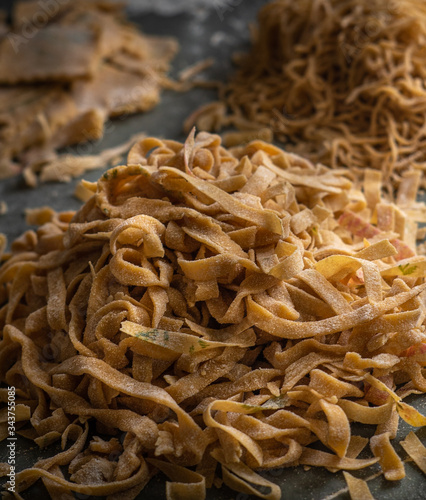 Process of making homemade wholewheat pasta in a kitchen with pasta sheet roller. Close up view. Dark photography