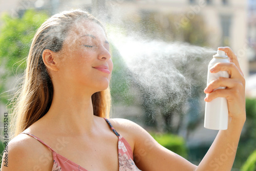 Fotografi Young woman spraying Thermal Water on her face outside