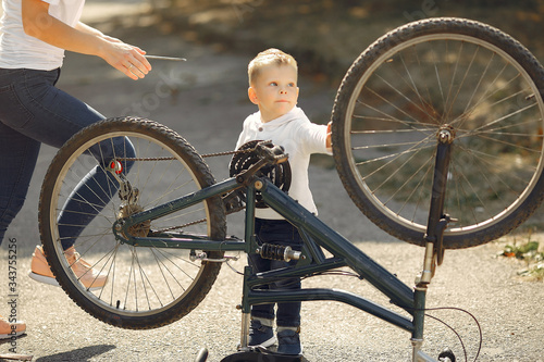 Family in a park. Mother with son. People repare the bike.