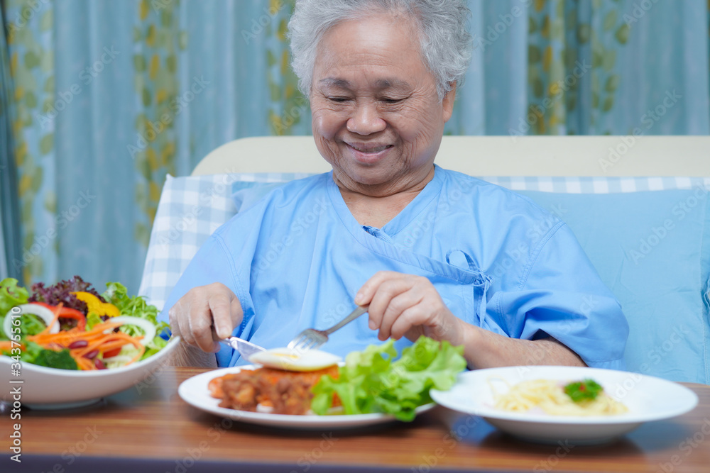 Asian senior or elderly old lady woman patient eating breakfast vegetable healthy food with hope and happy while sitting and hungry on bed in hospital. Asian senior or elderly old lady woman patient eating breakfast vegetable healthy food with hope and happy while sitting and hungry on bed in hospital.