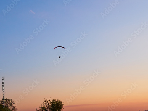 Paraglider flies on a paraglider over the city on a warm summer evening