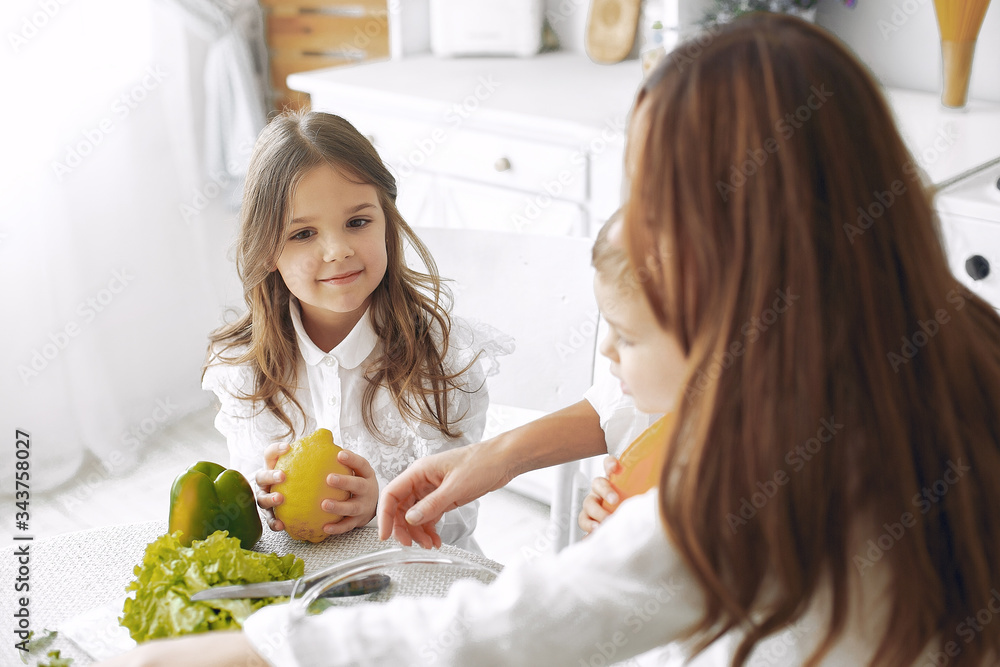 Family in a kitchen. Beautiful mother with children. Lady in white blouse. Family in a kitchen. Beautiful mother with children. Lady in white blouse.