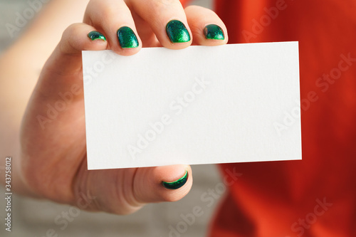Girl's hand holding blank white business card close up