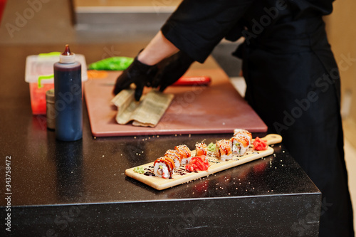 Close up hands of professional chef wear in black gloves making sushi and rolls in a restaurant kitchen of japanese traditional food.