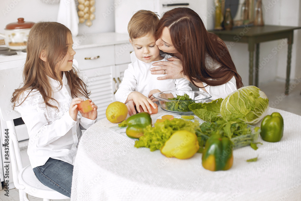 Family in a kitchen. Beautiful mother with children. Lady in white blouse. Family in a kitchen. Beautiful mother with children. Lady in white blouse.
