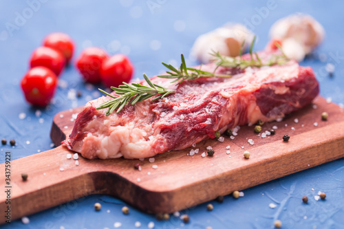 Fresh raw meat for steak on wooden cutting board.
