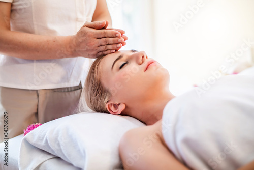 Beautiful young attractive Caucasian woman having head massage by Thai Masseur in spa salon. Beauty treatment and body care lifestyle concept