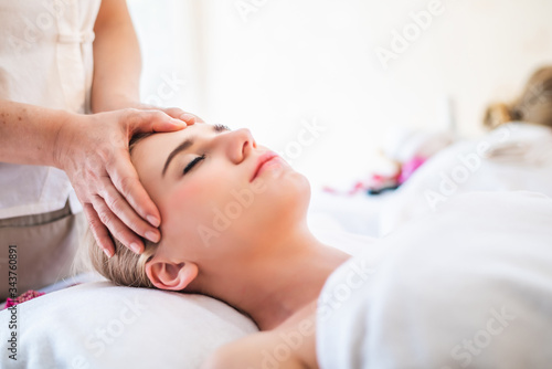 Beautiful young attractive Caucasian woman having head massage by Thai Masseur in spa salon. Beauty treatment and body care lifestyle concept