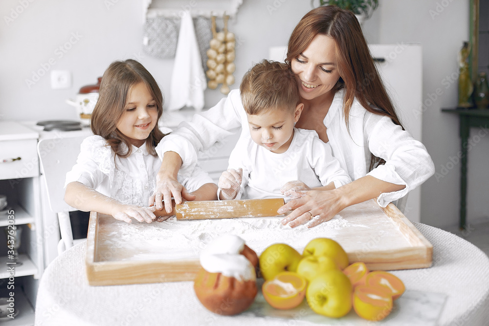 Family in a kitchen. Beautiful mother with children. Lady in white blouse.