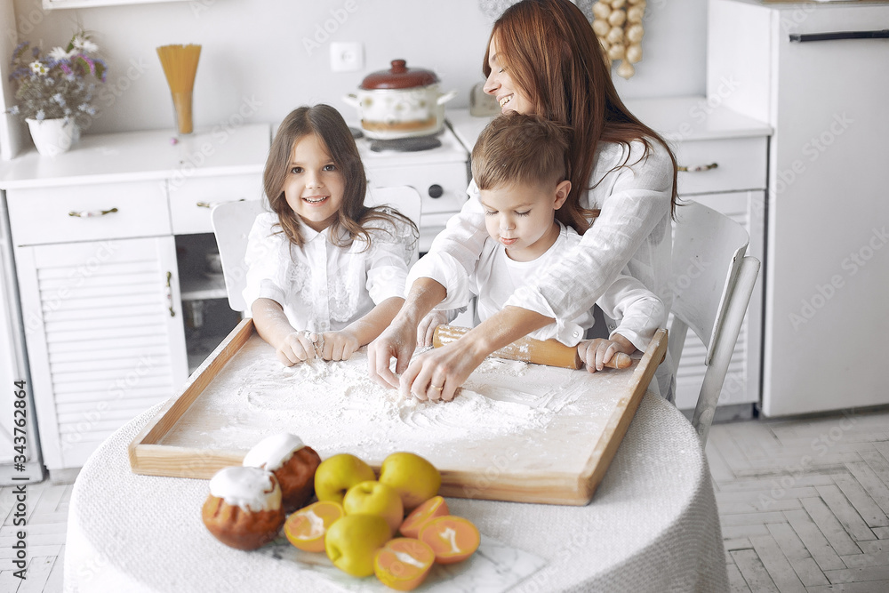 Family in a kitchen. Beautiful mother with children. Lady in white blouse.